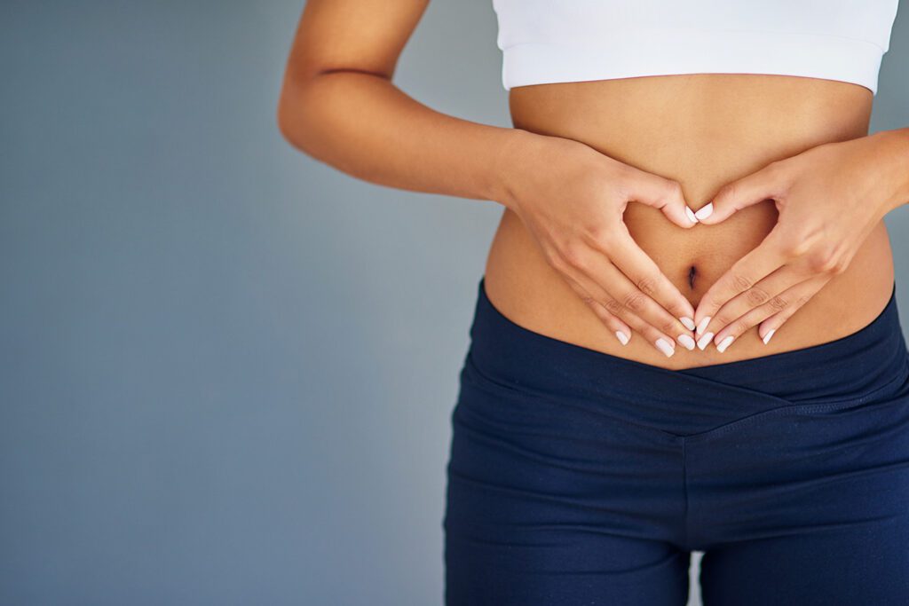 Woman making a heart shape over her abdomen to focus on gut health.