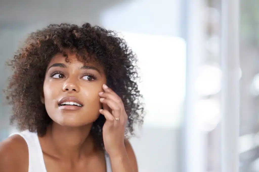 Woman checking her skin in the mirror wondering if what she's eating is affecting her skin.