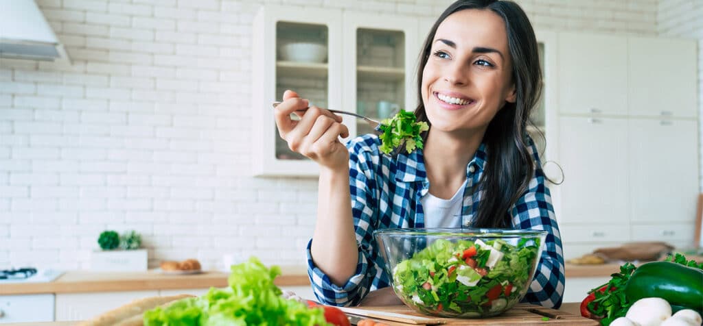 Woman eating a salad to optimize her nutrition for better skin health.