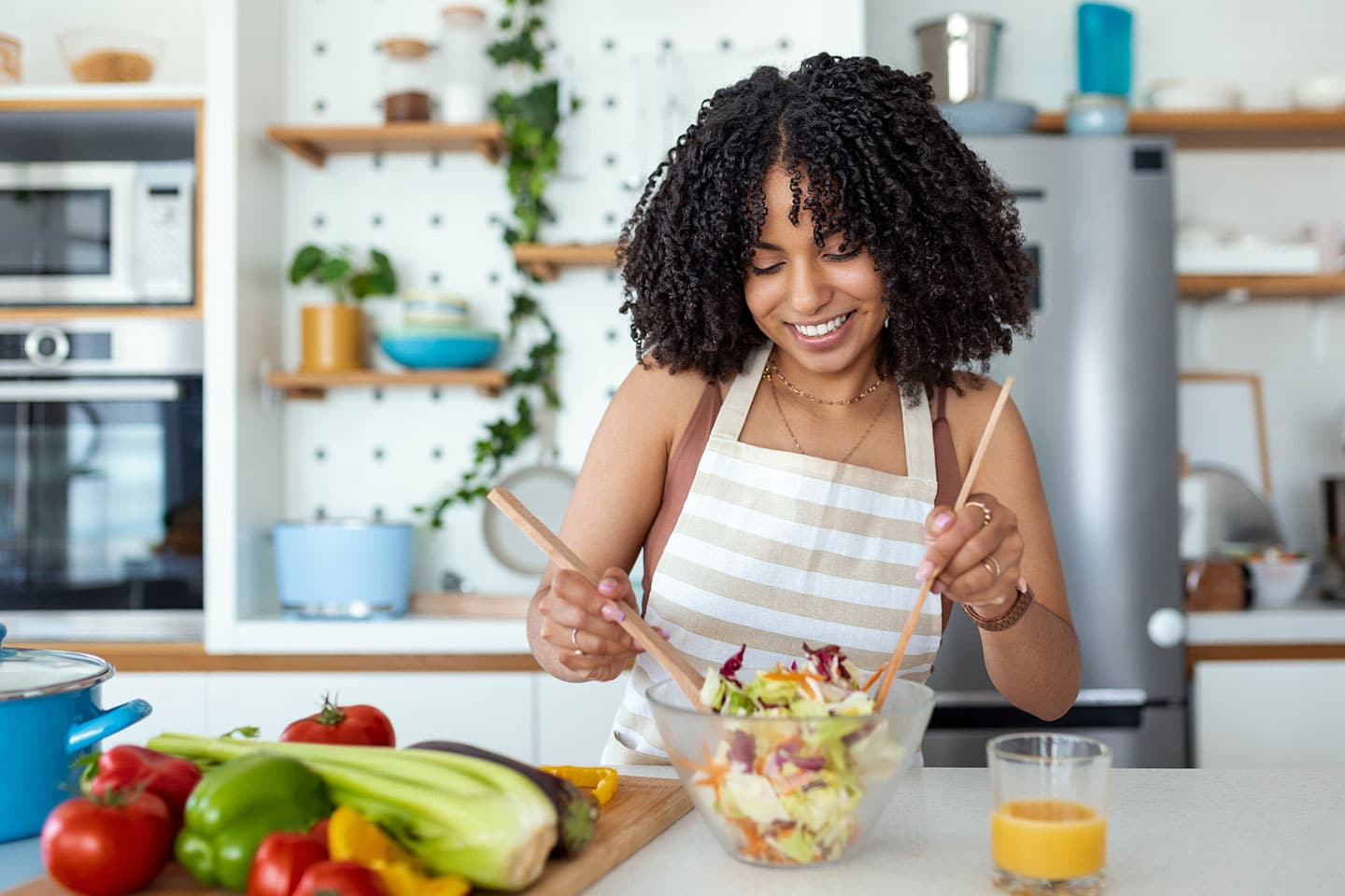 woman fixing a salad along with other vegetables to improve her skin health.