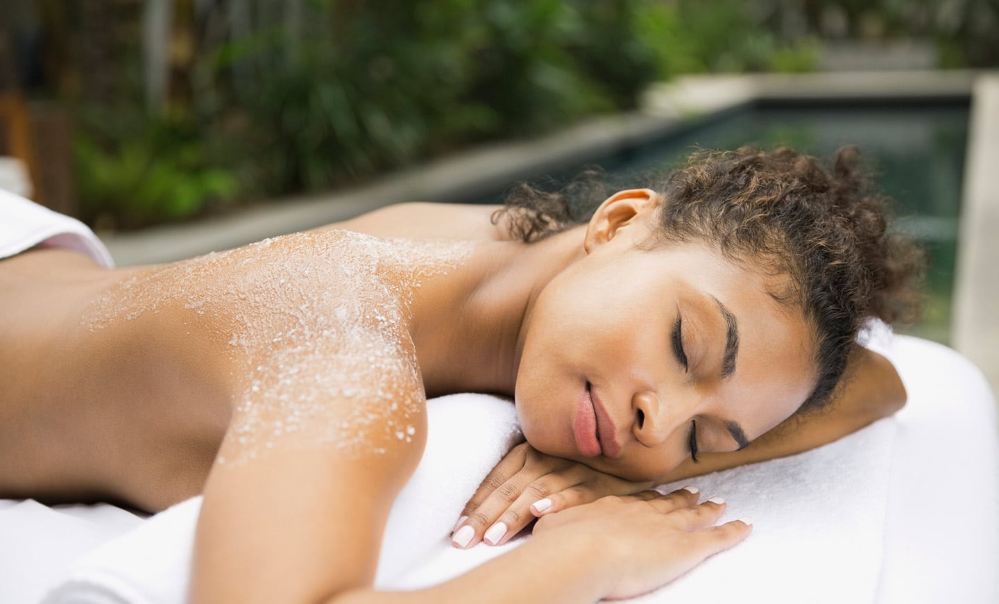Woman relaxing after getting a body peel exfoliant placed on her back.