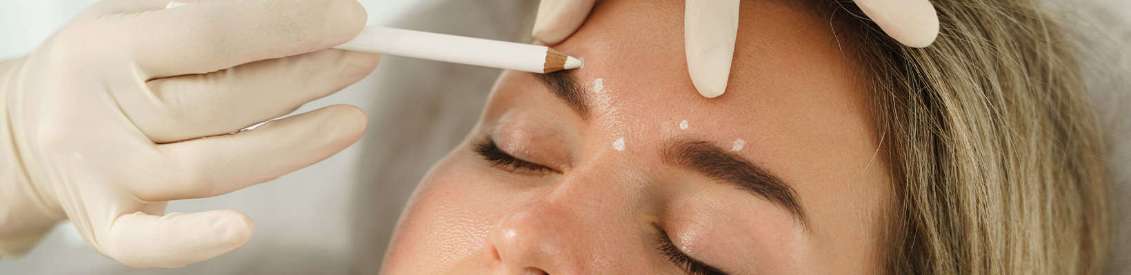 Doctor making marks on client's face before filler injection